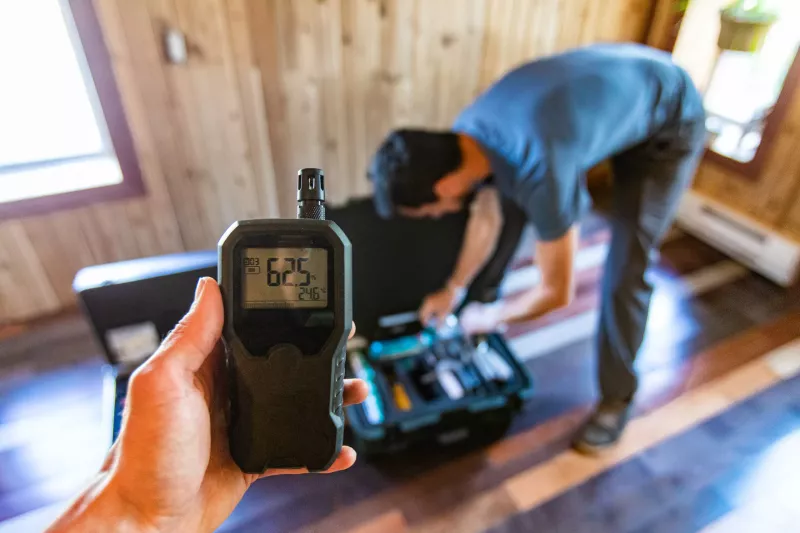 A first person perspective of a person using an indoor air quality monitor device, checking for allergens, particles and CO2 during a domestic home inspection.