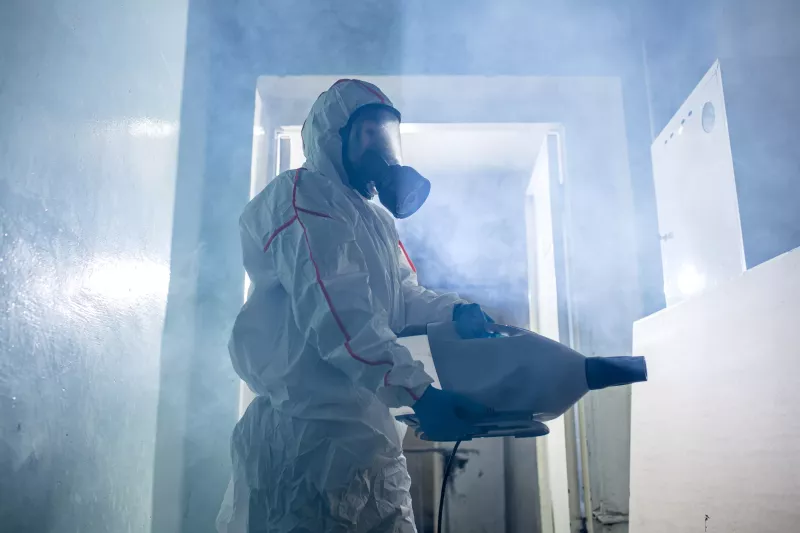 World pandemic COVID-19. professional disinfector in protective suit indoors, kill and remove bacterias from surfaces in isolated space. coronavirus concept